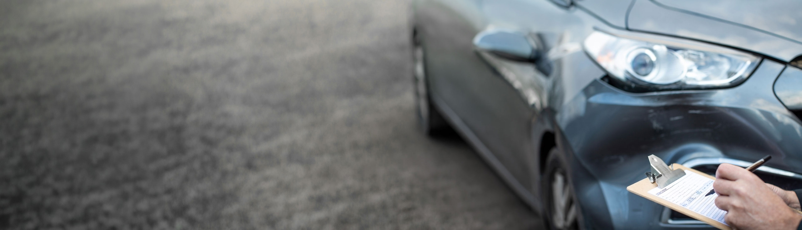 Sachverständiger untersucht den Schäden am Auto und füllt einen Reparaturvoranschlag aus.